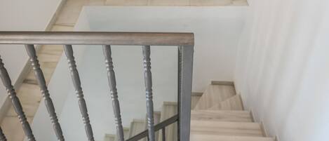 A staircase with a wooden handrail and a black and white artwork above it.
