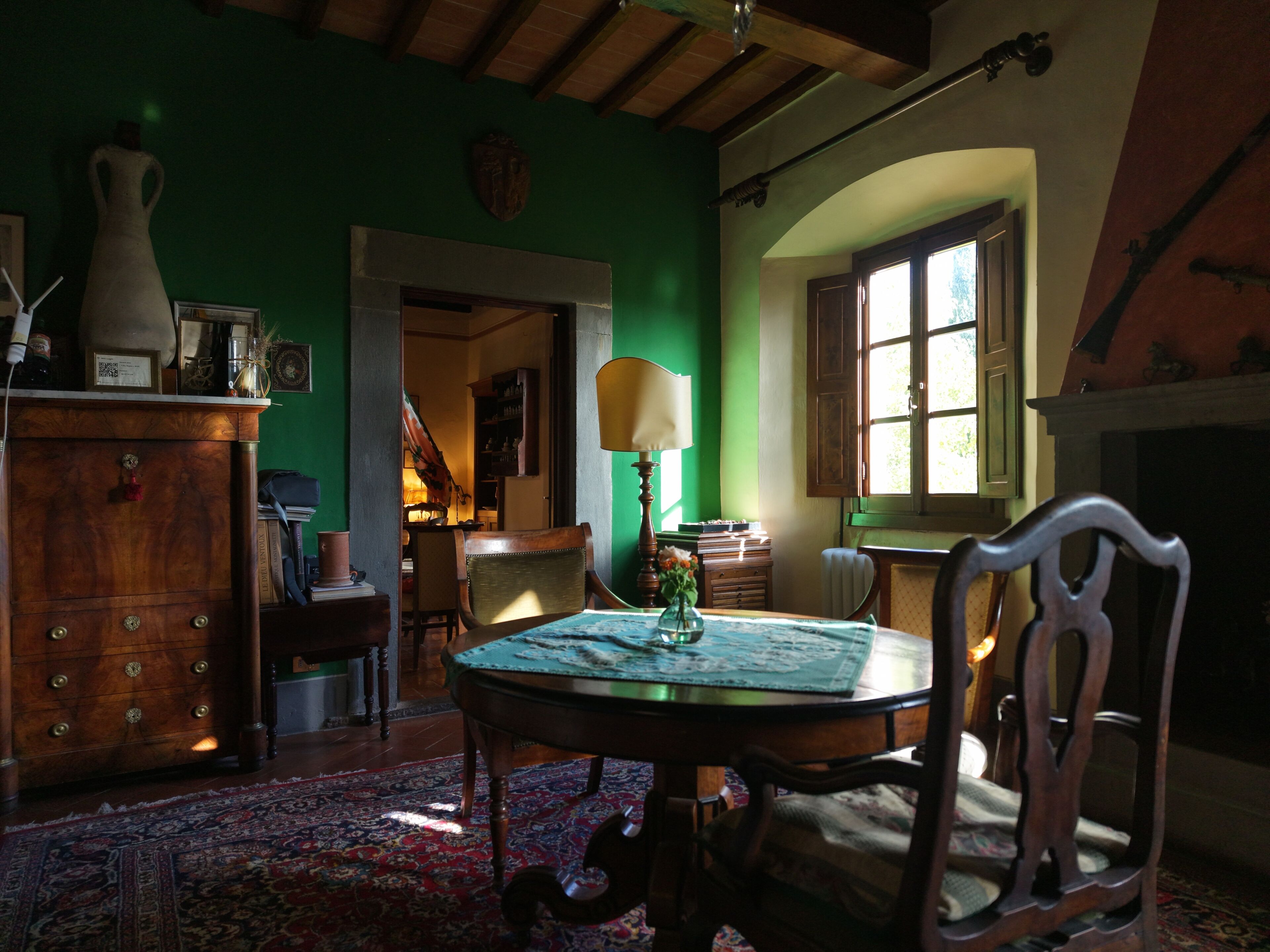 Una habitación con una mesa de madera, sillas, chimenea y una pared verde.