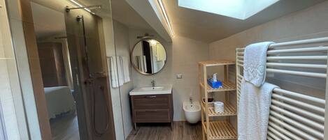Un baño moderno con tragaluz, cabina de ducha de vidrio, tocador de madera y estante empotrado con toallas.