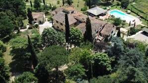 An aerial view of a villa with a swimming pool, surrounded by lush greenery and tall trees. - Villa Rigacci (Reggello)