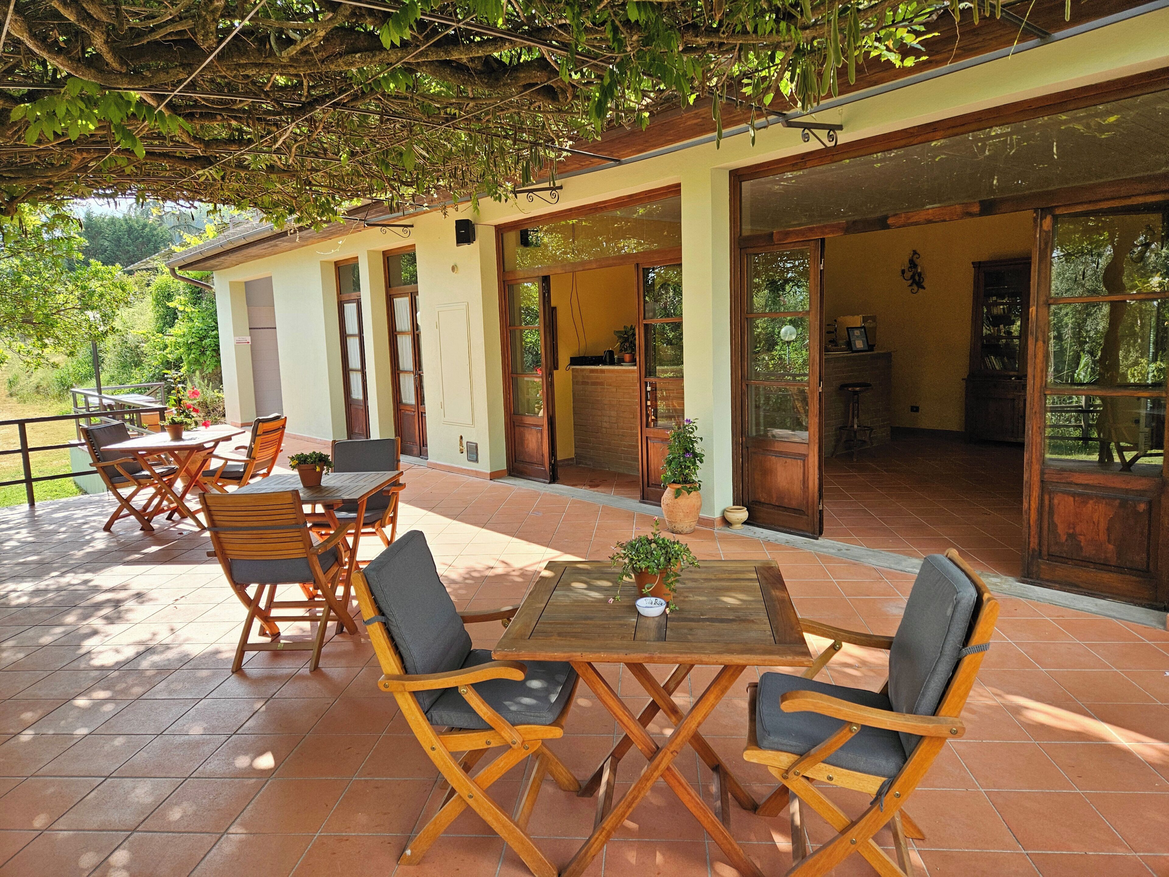 An outdoor patio with wooden furniture, a table, and potted plants.