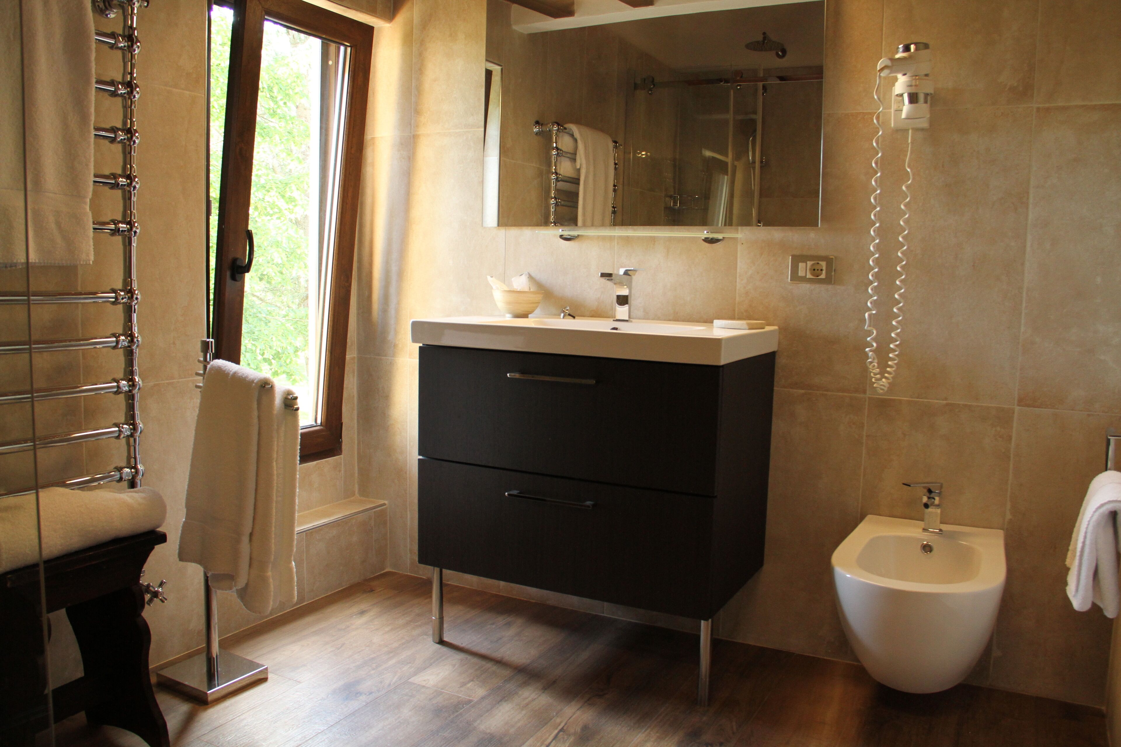 Un baño moderno con bañera, lavamanos, lavavaterino y ventana.