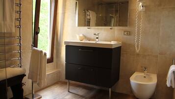 Un baño moderno con bañera, lavamanos, lavavaterino y ventana.