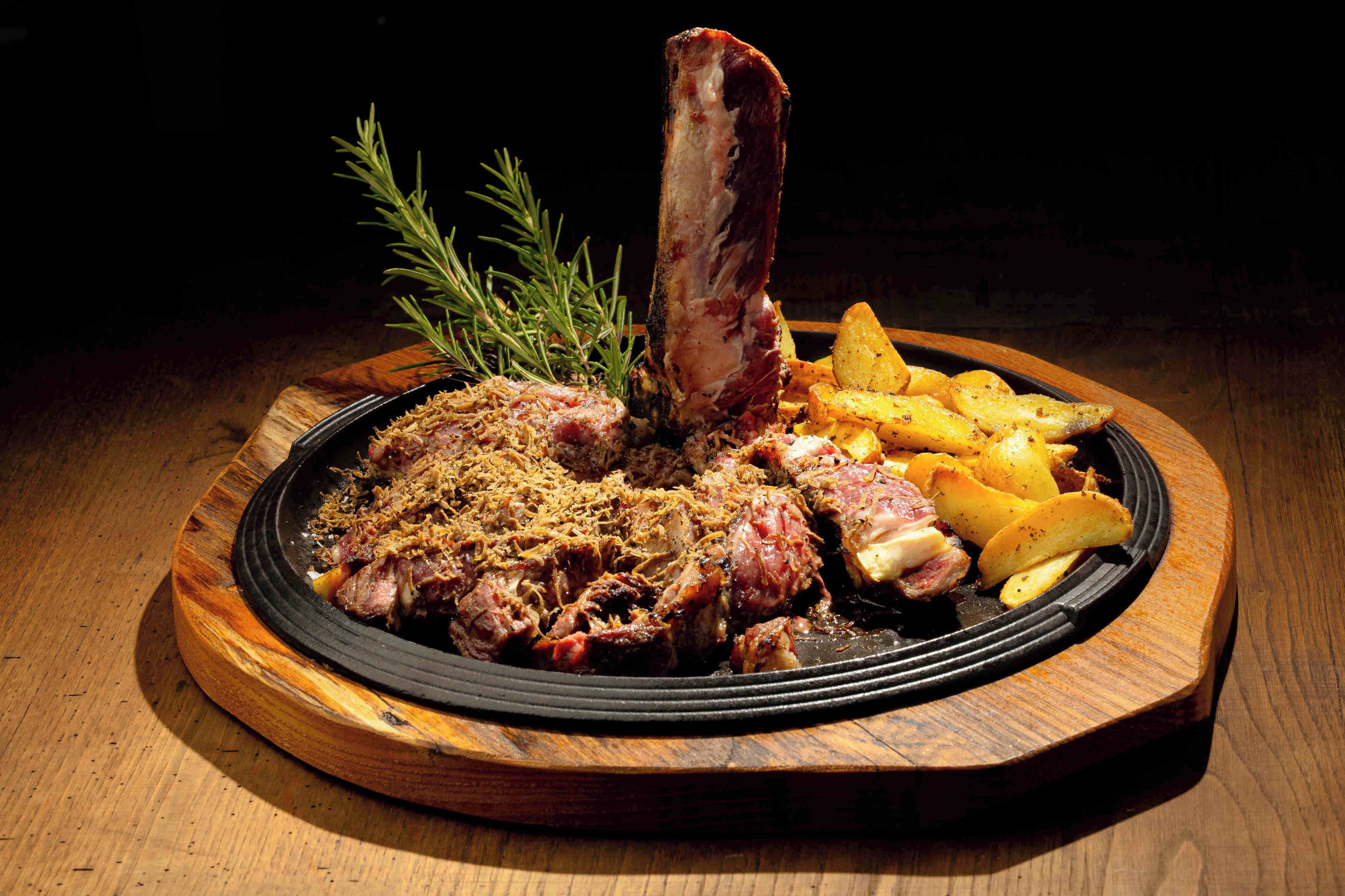 A plate of food with a bone, meat, and potatoes.