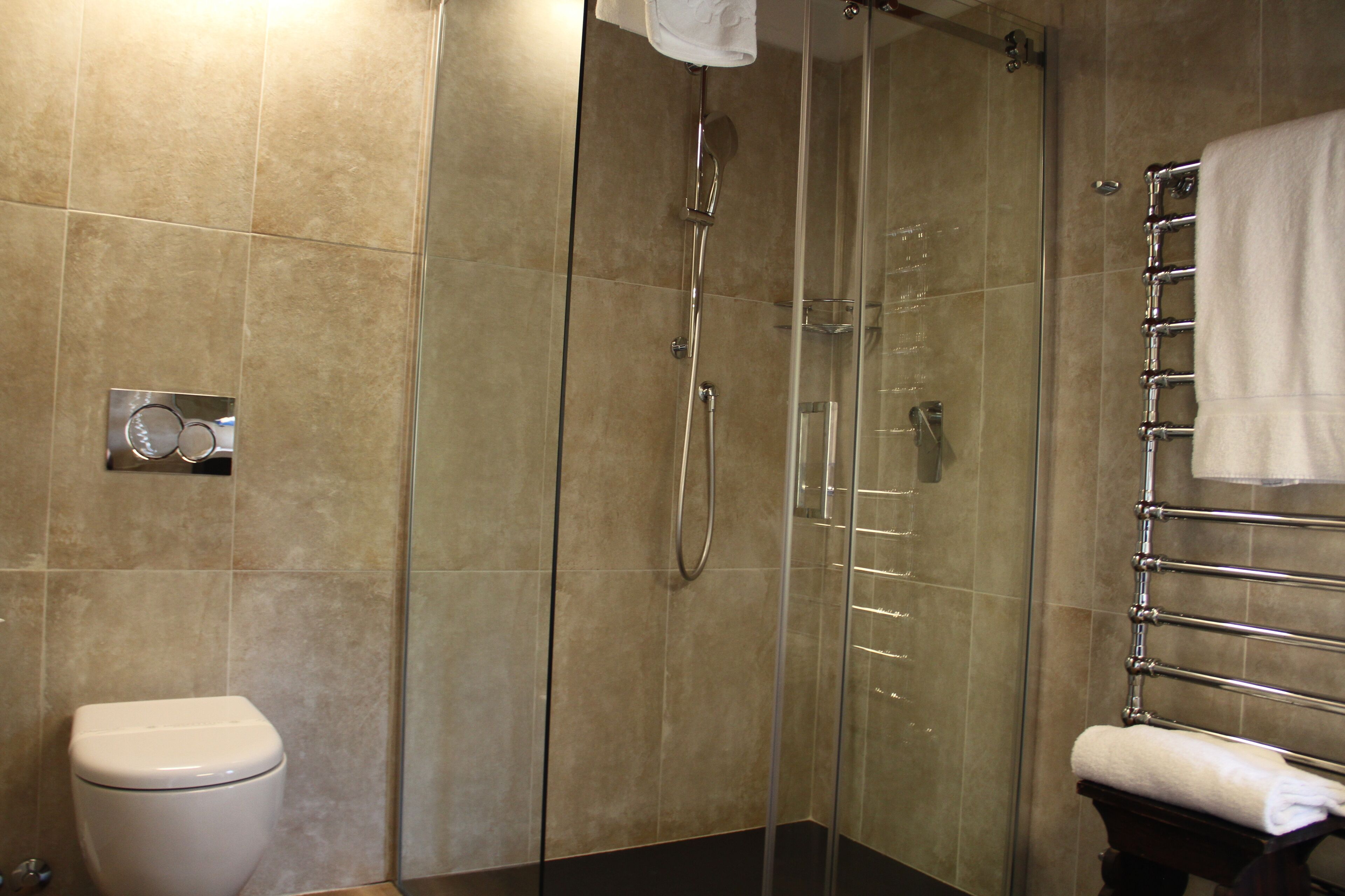 A modern bathroom with a glass-enclosed shower, a toilet, and a towel rack.