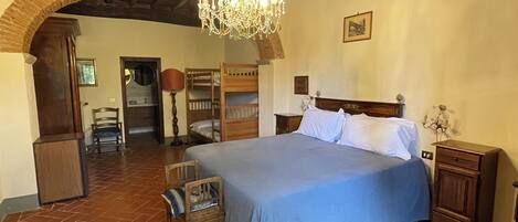 Une chambre à coucher avec un grand lit, une tête de lit en bois, un lustre et une arche rustique.