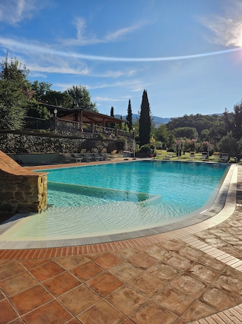 Piscina all'aperto, una piscina a sfioro, ombrelloni da piscina, lettini. Villa Rigacci
