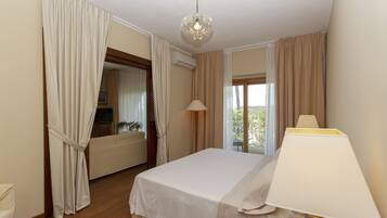 A hotel room with a bed, a lamp, a telephone, and a view of the outdoors.