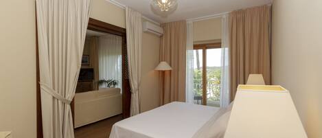A hotel room with a bed, a lamp, a telephone, and a view of the outdoors.