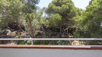 Ein Balkon mit Blick auf einen felsigen Garten mit Bäumen und Sträuchern.