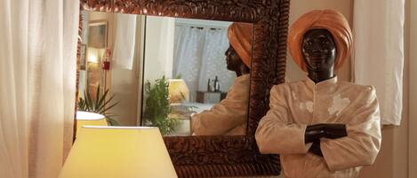 A mannequin dressed in traditional attire with a turban, standing in front of a mirror with an ornate frame.