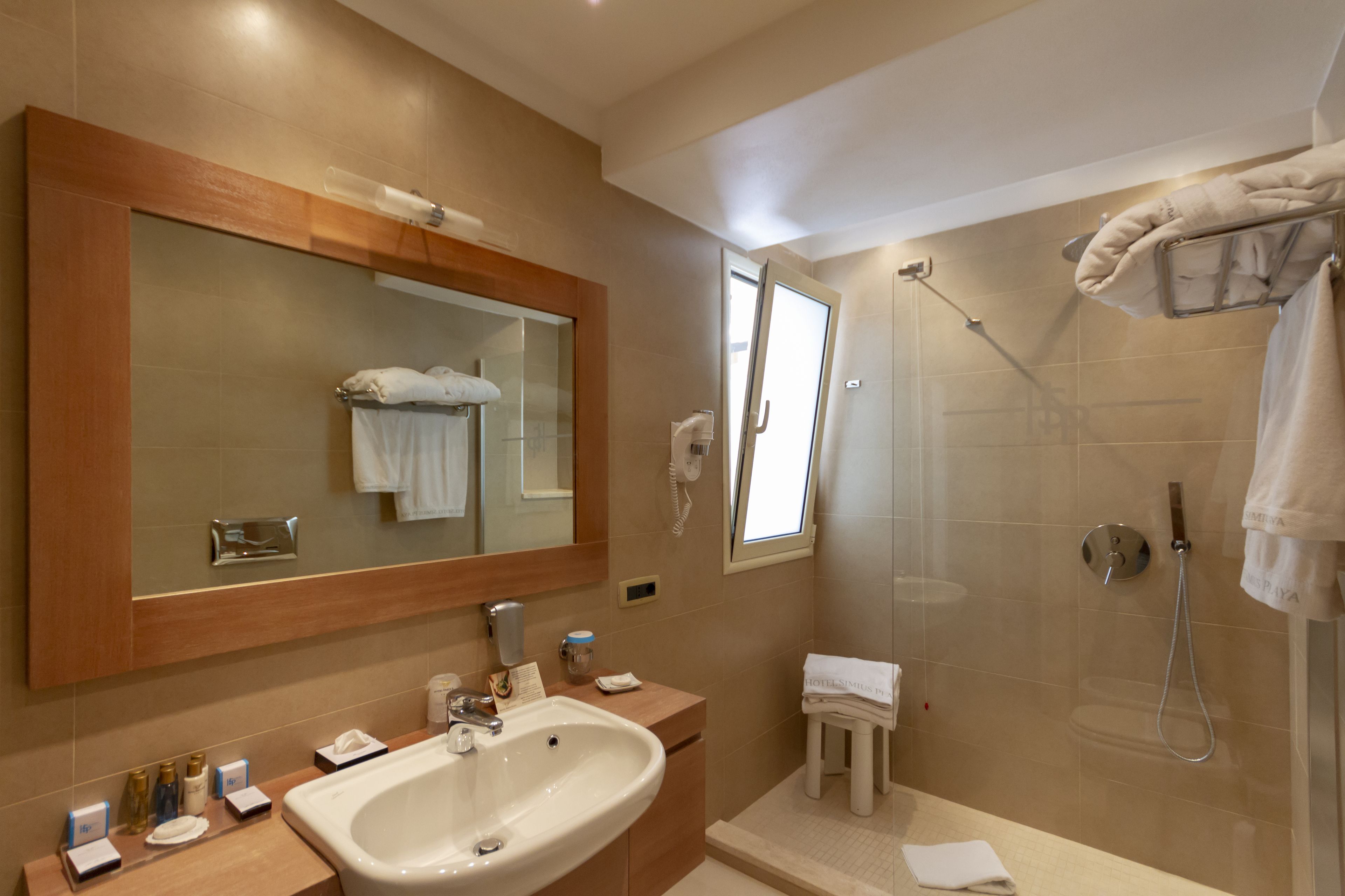 A modern bathroom with a large mirror, a sink, a shower, and a vanity with toiletries.