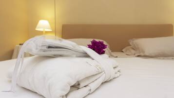 A neatly made bed with white linens and a purple flower decoration.