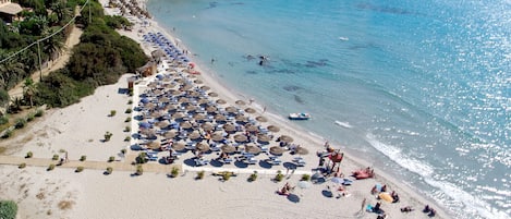 Een privéstrand, wit zand, ligstoelen aan het strand, parasols