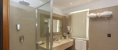 A modern bathroom with a glass shower enclosure, dual sinks, and a toilet.