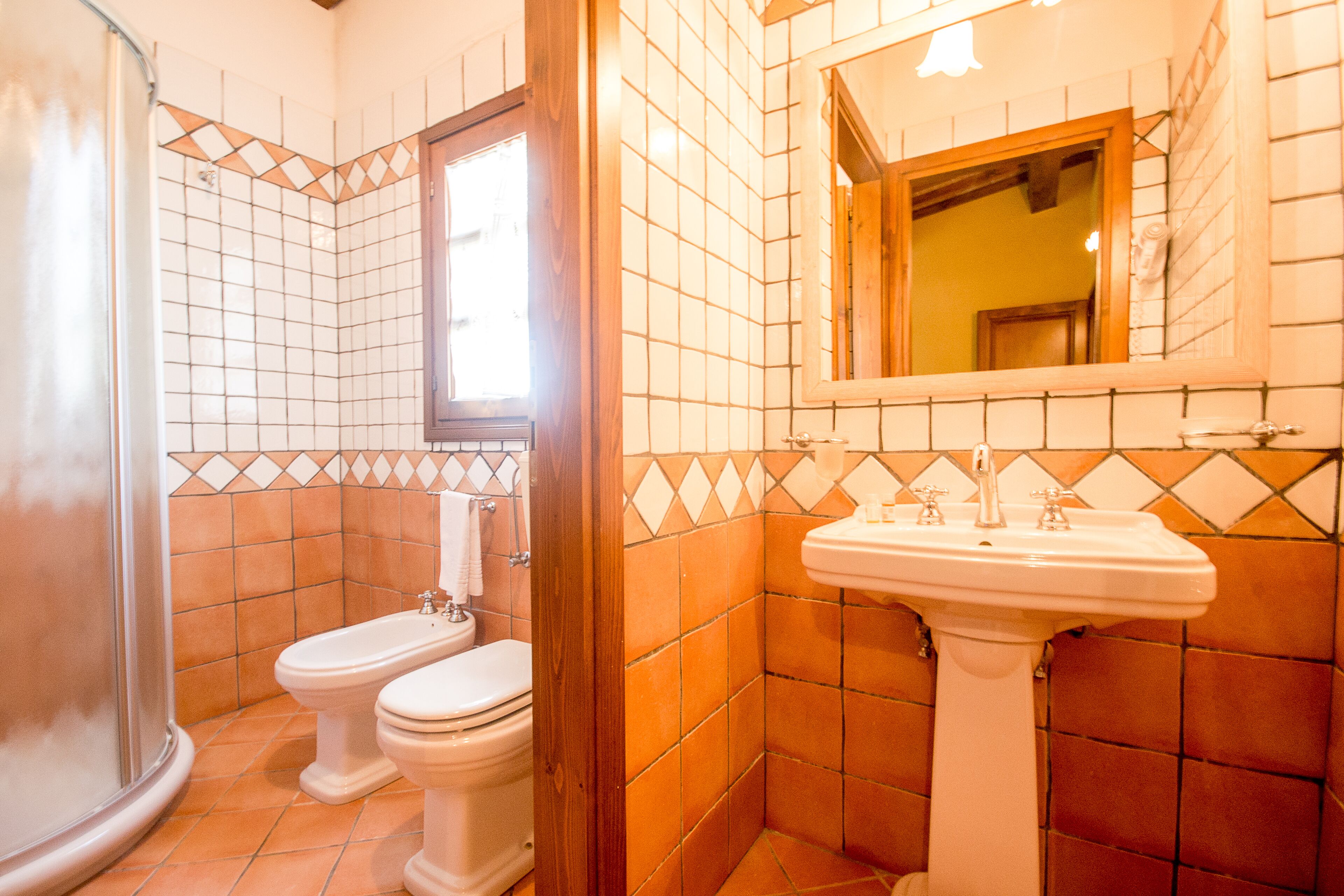 Une salle de bain avec deux toilettes, un lavabo et une douche.