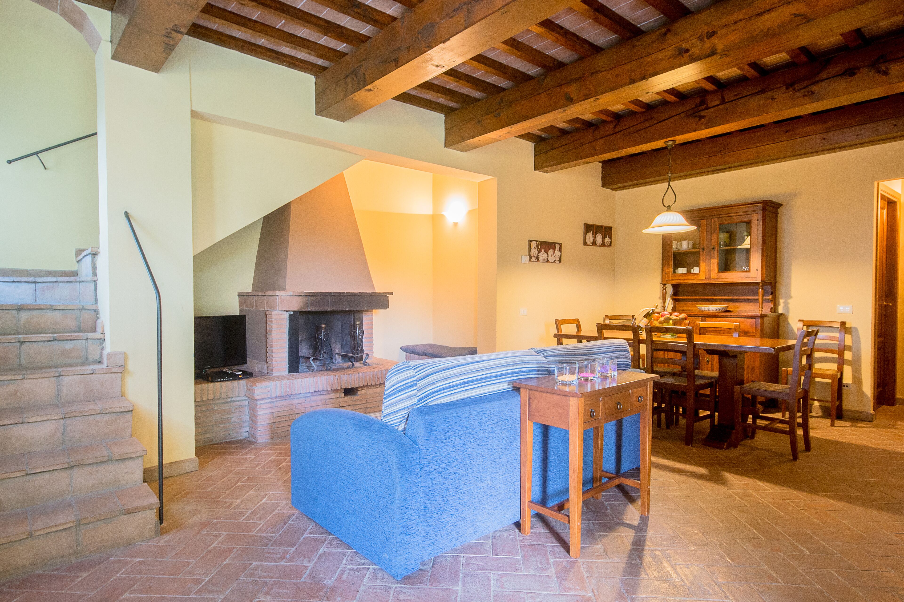 A cozy living room with a fireplace, a dining area, and a staircase leading to another level.