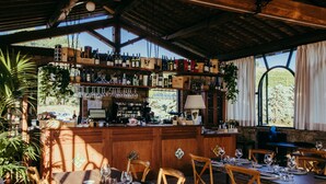 Een restaurant met een houten bar, gedekte tafels en uitzicht op de omgeving.