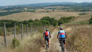 Two cyclists on a rural path with rolling hills in the background.