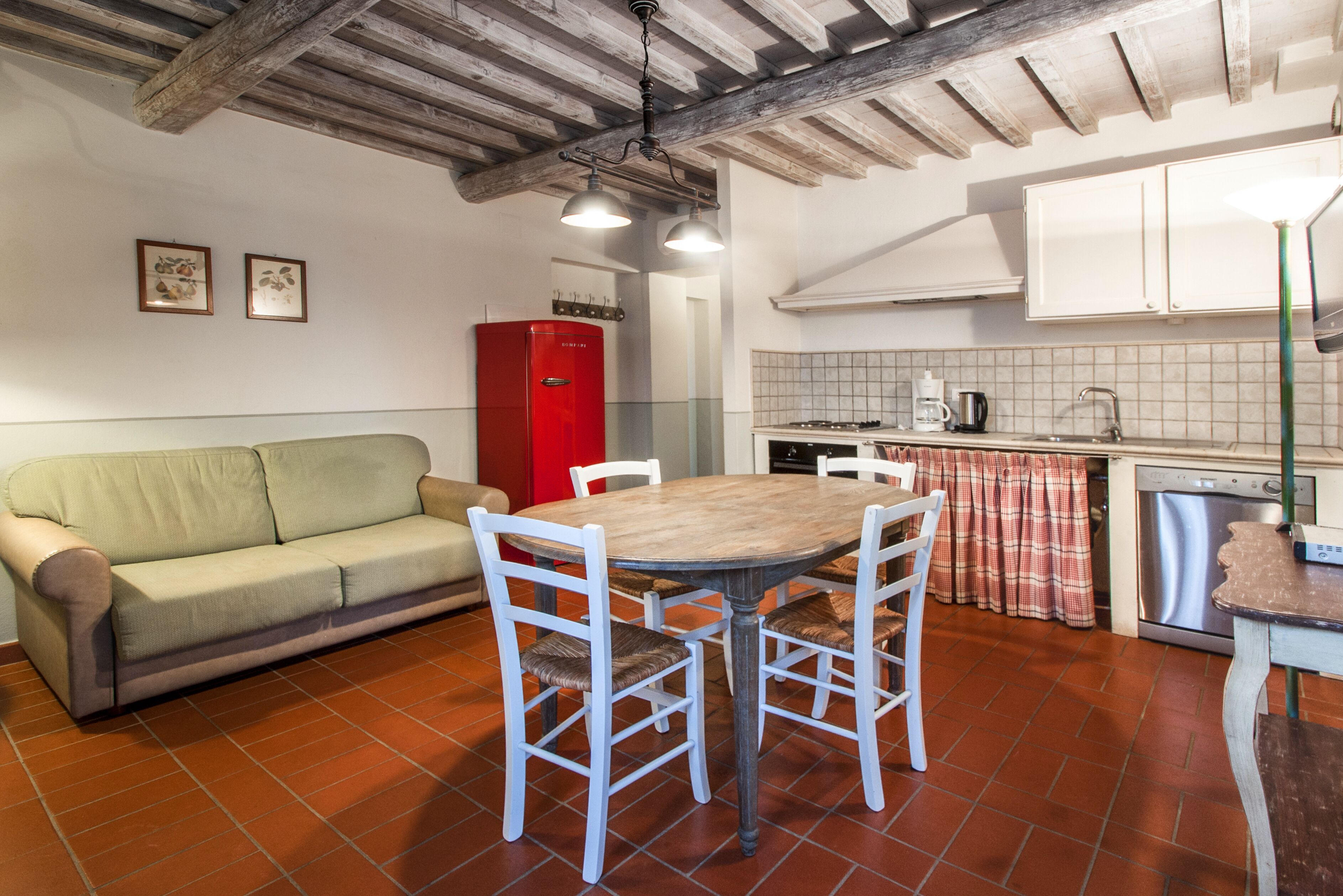 A cozy kitchen with a dining table, chairs, a red refrigerator, and a tiled backsplash.