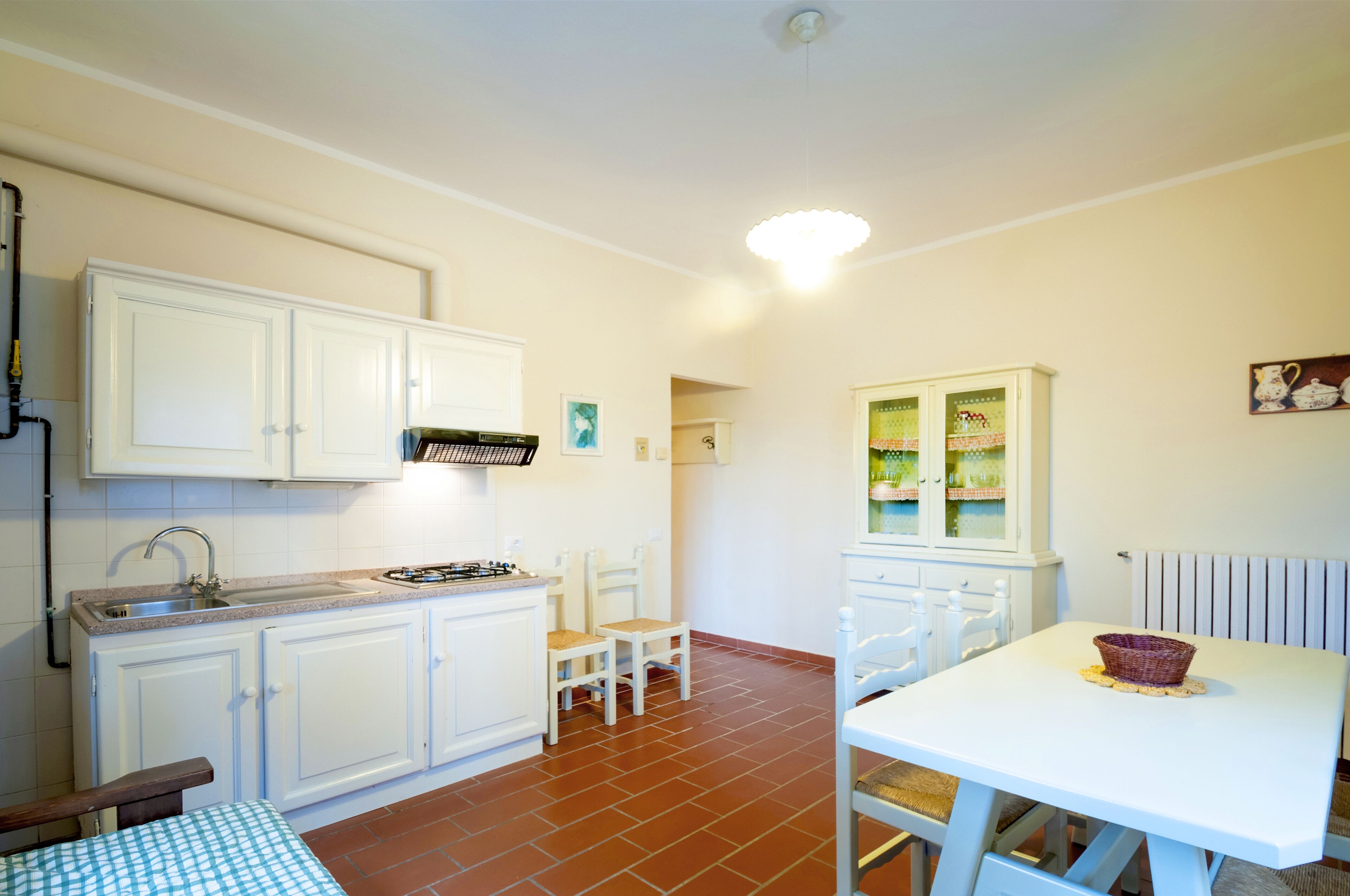 Cocina compacta con alacenas blancas, estufa a gas y comedor con mesa y sillas.