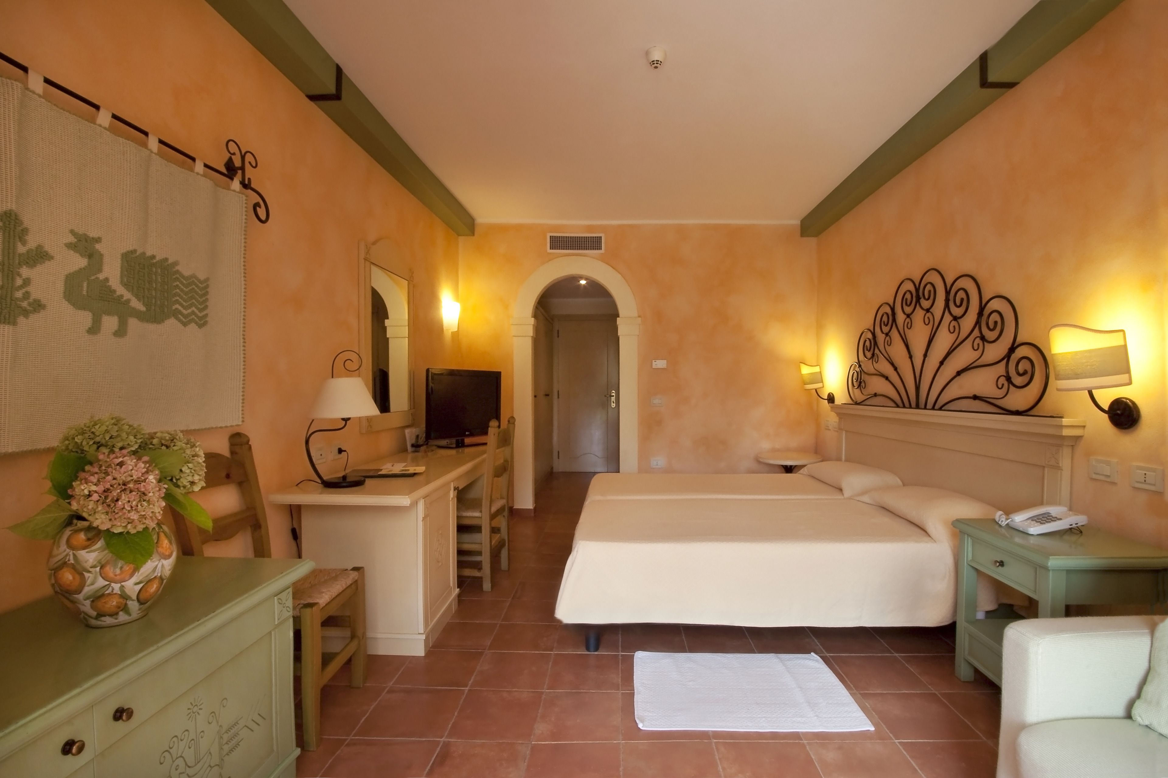 A hotel room with a bed, desk, TV, and a decorative wall piece.