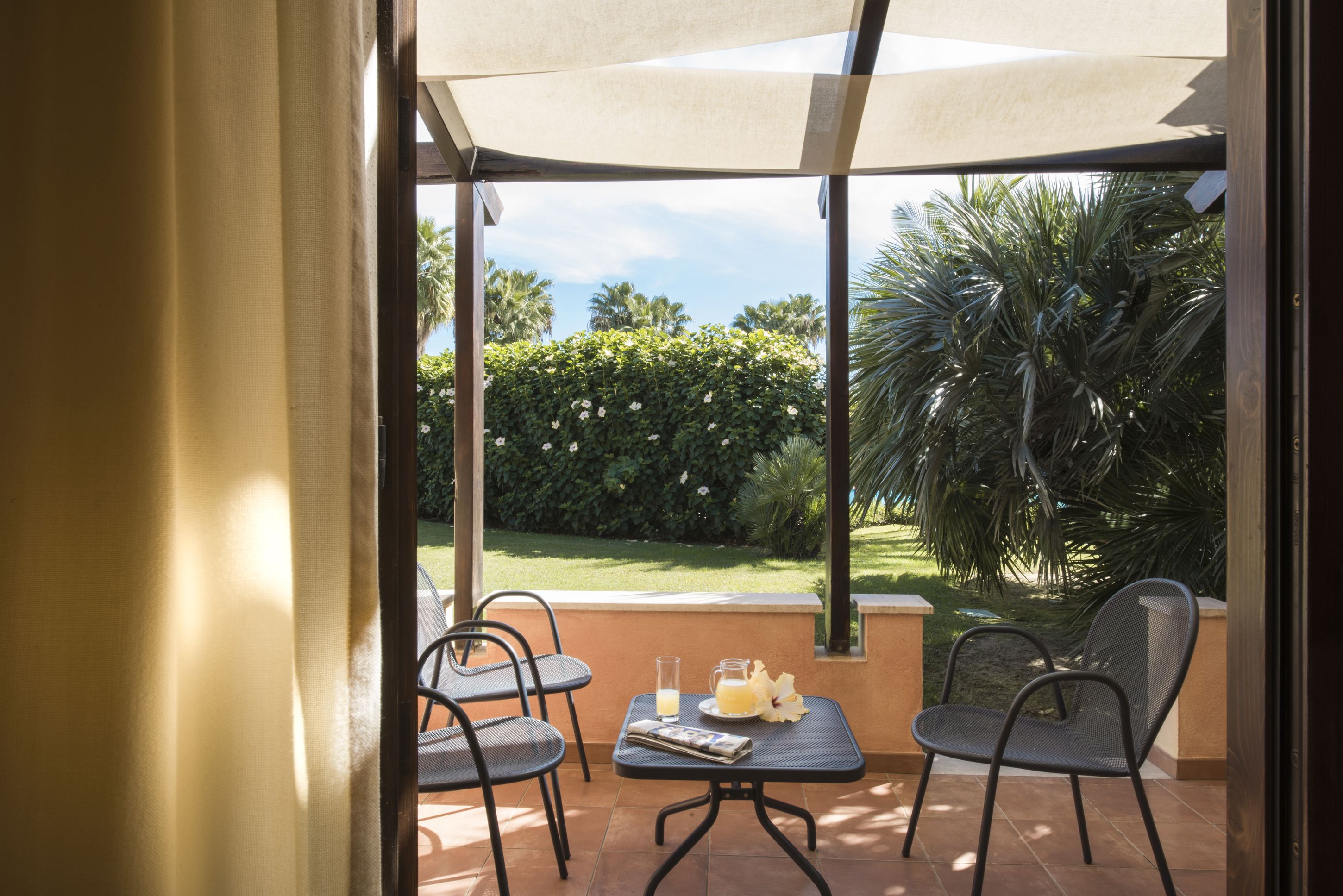 A patio with two chairs, a table, and a drink.