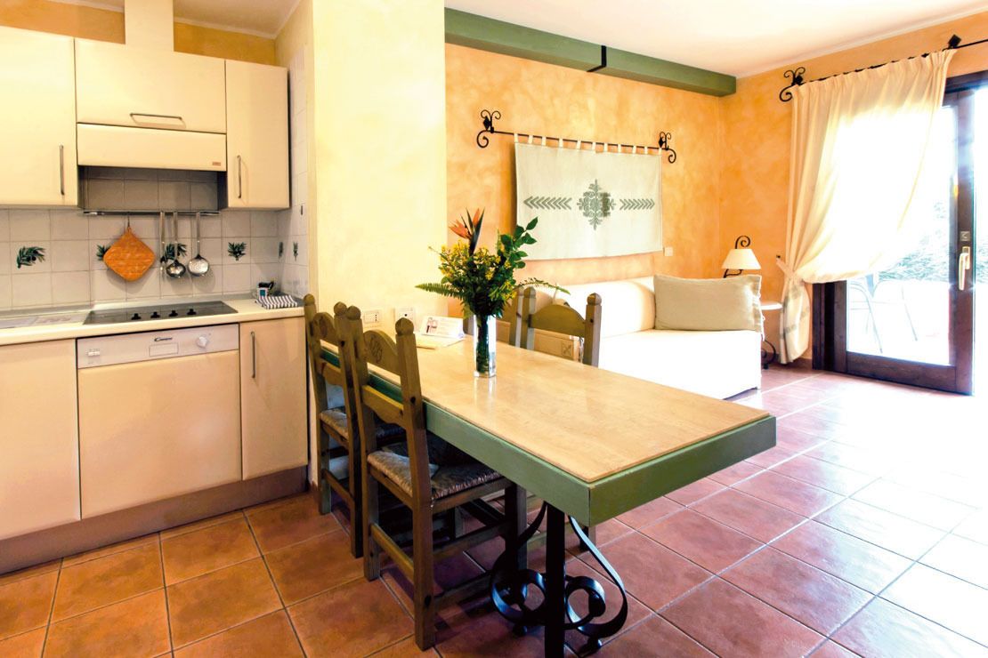 A compact kitchen with white cabinets, a dishwasher, and a dining area with a table and chairs.