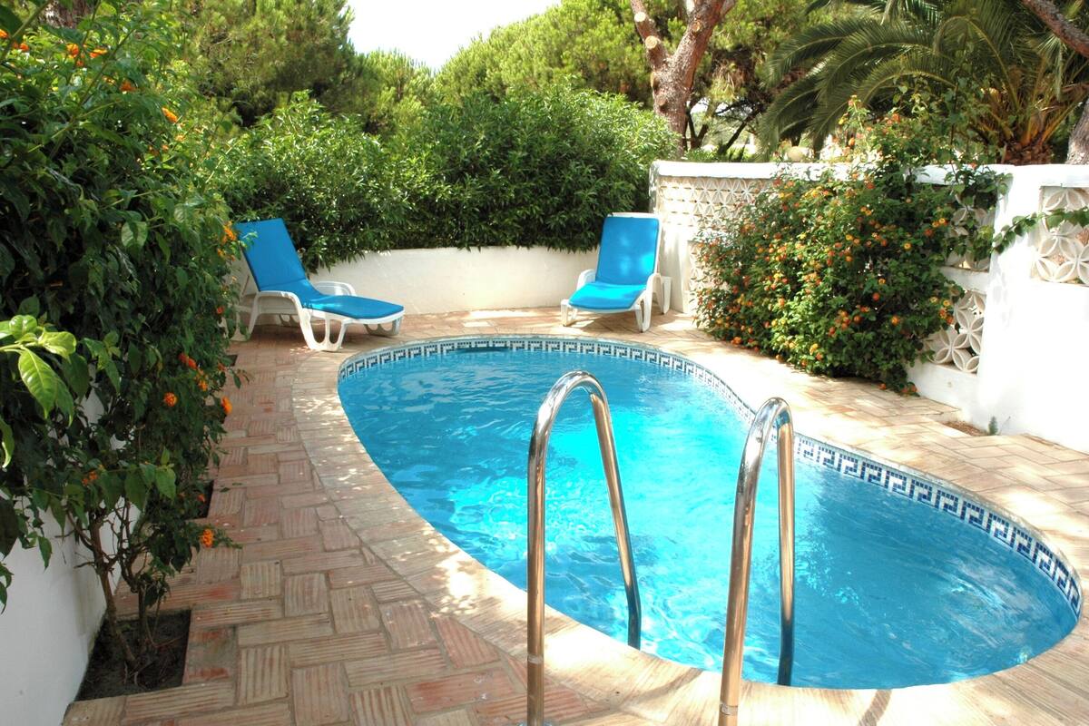 Una piscina con due sdraio blu e una scala in metallo.