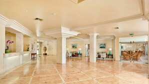 A spacious lobby with marble flooring, a reception desk, seating areas, and a glass door leading to another room. - Vale Do Garrão Villas (Loulé)