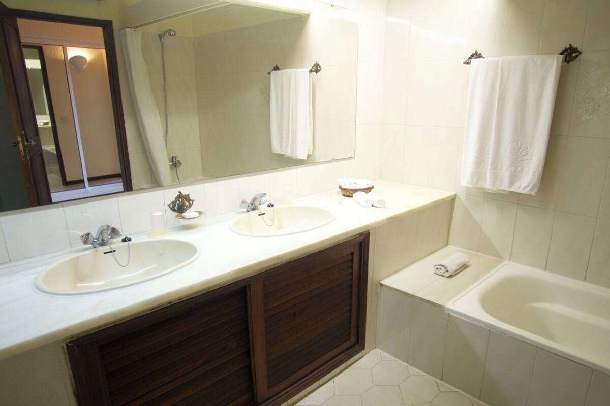 Un bagno con due lavandini, una vasca e uno specchio grande.