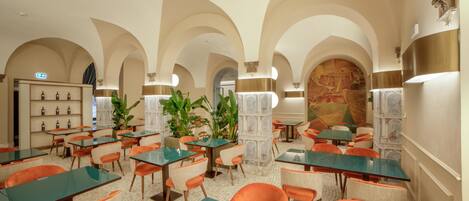 Un restaurante con varias mesas y sillas, techo abovedado y una pared con un mural.