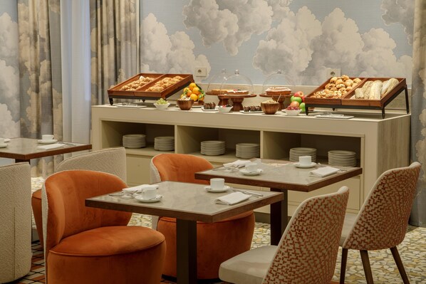 Un buffet de petit-déjeuner proposant une variété d’aliments, ainsi qu’un espace repas avec des tables et des chaises.
