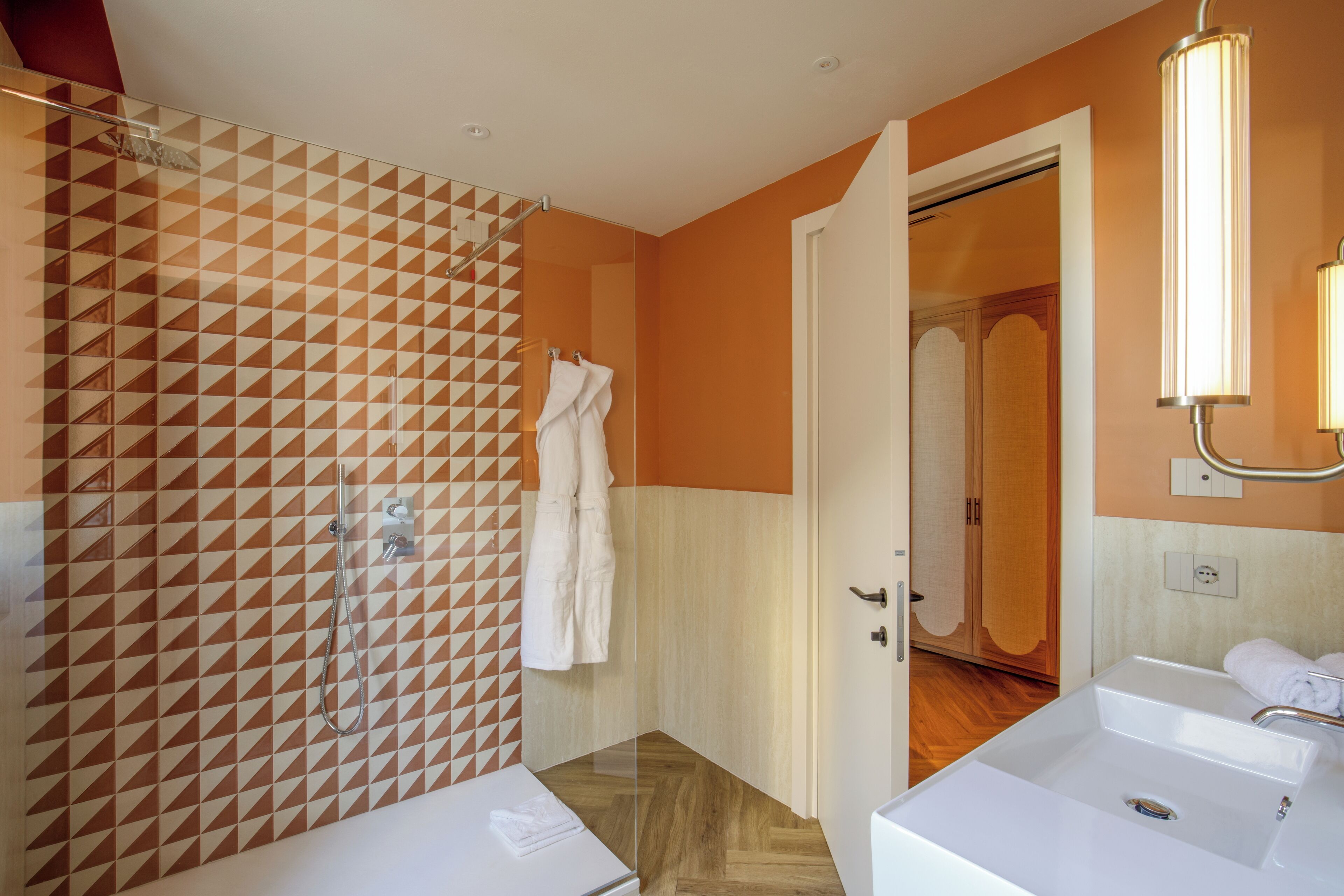 A bathroom with a geometric patterned wall, a shower, and two sinks.
