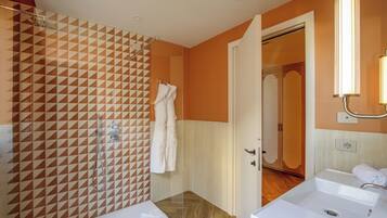 Un baño con pared de diseño geométrico, una ducha y dos lavamanos.
