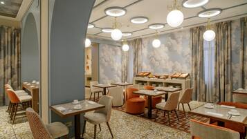 Comedor de hotel con mesas redondas, sillas y un bufé.