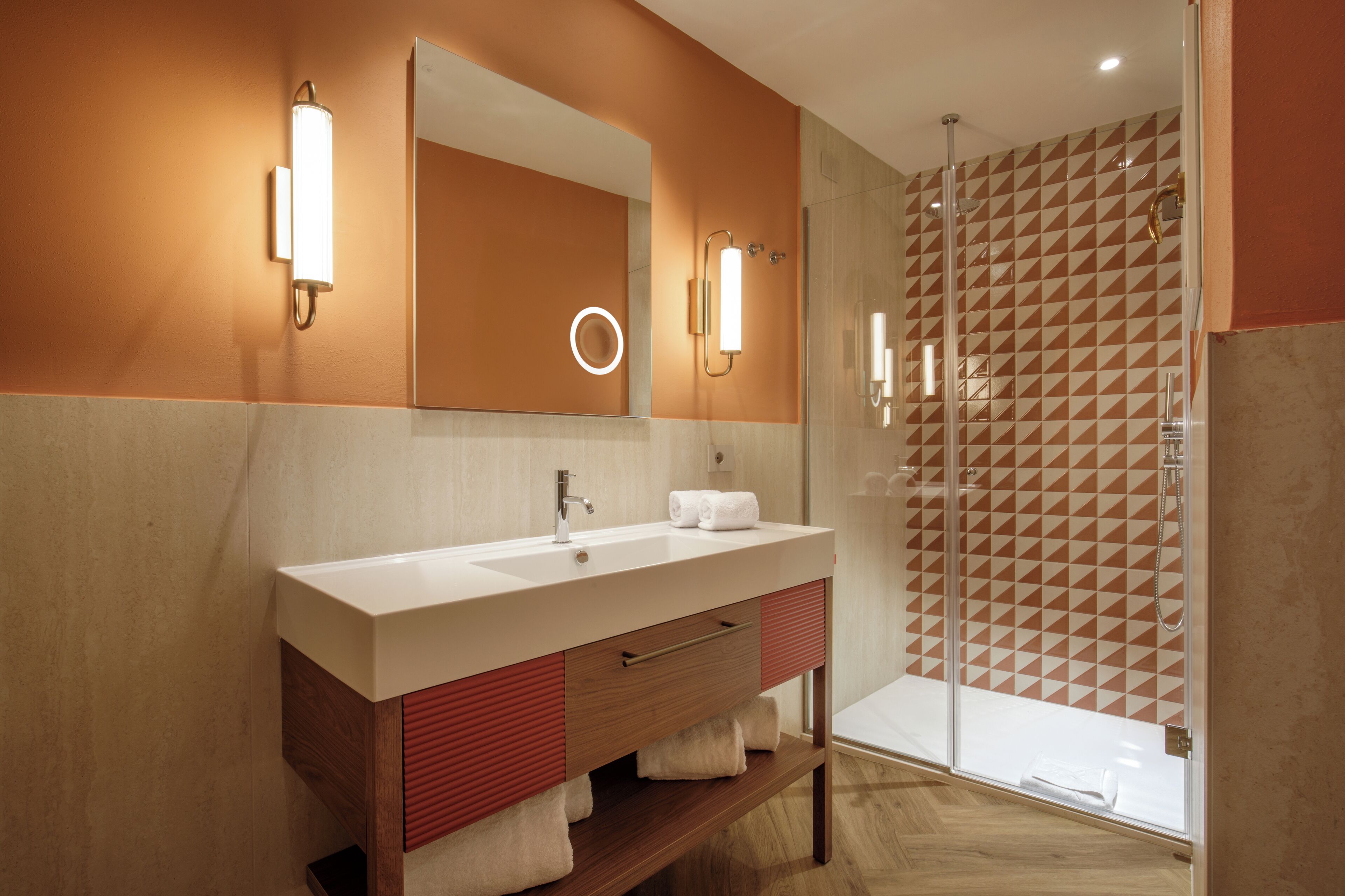 Une salle de bain moderne avec un grand miroir, deux lavabos et un espace douche.