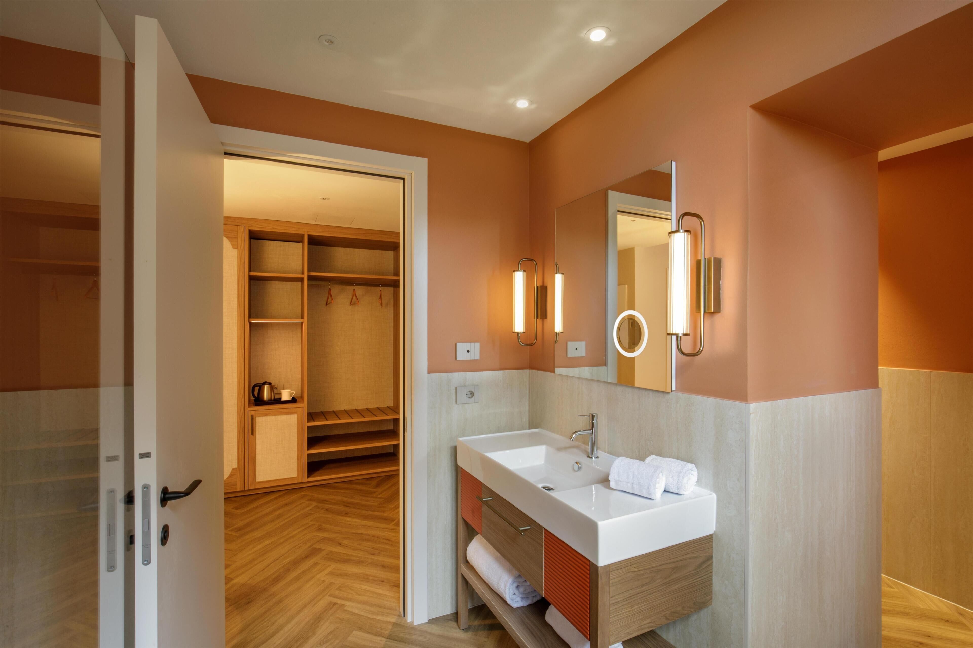A modern bathroom with a white sink, mirror, and towel rack.