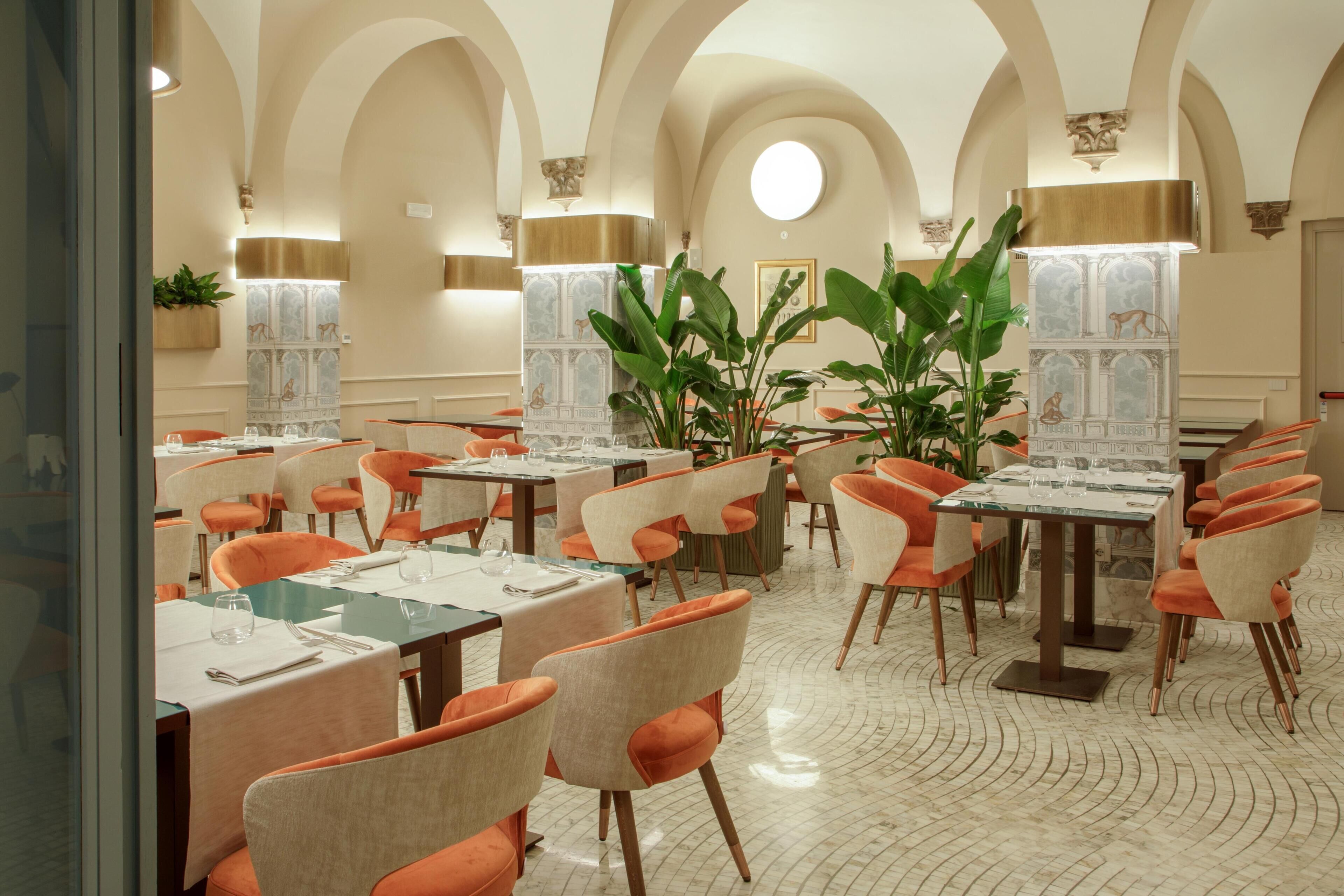 Een restaurant met meerdere tafels en stoelen, een gewelfd plafond en decoratieve wandpanelen.