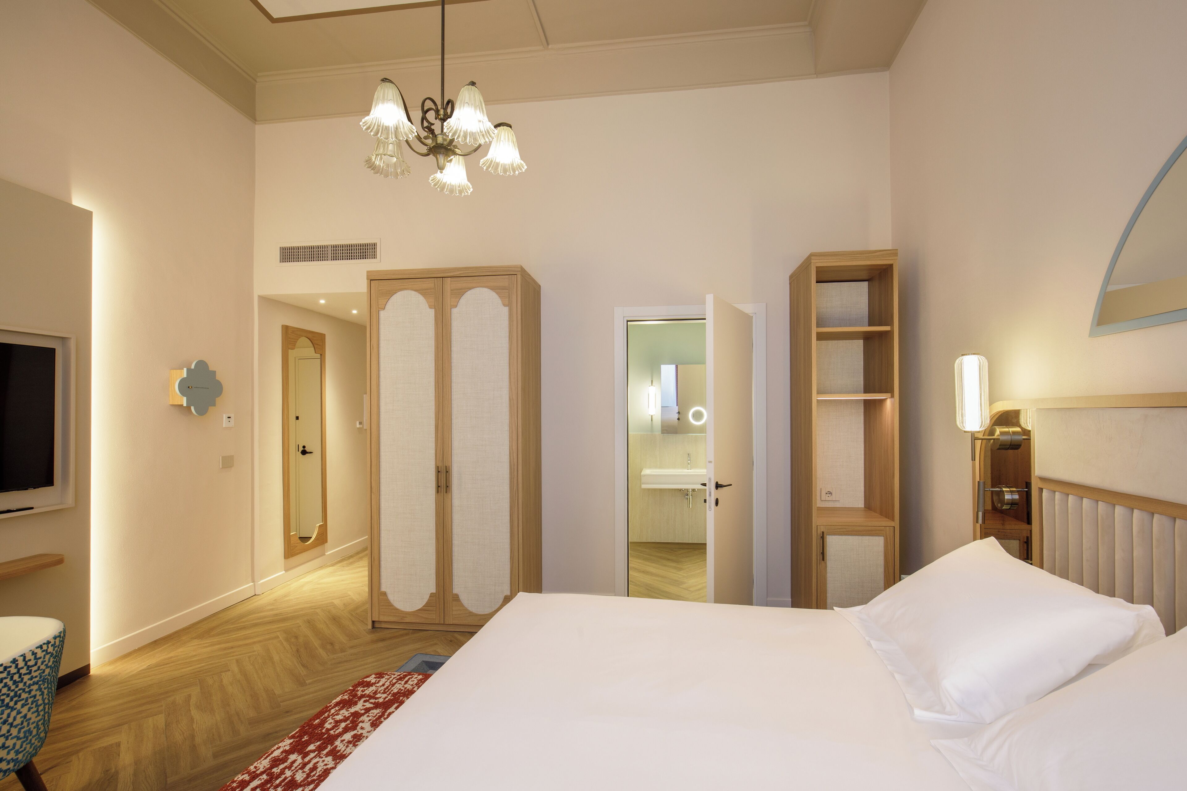Una habitación de hotel con una cama grande, televisor, armario y espejo.