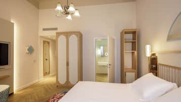 Una habitación de hotel con una cama grande, televisor, armario y espejo.