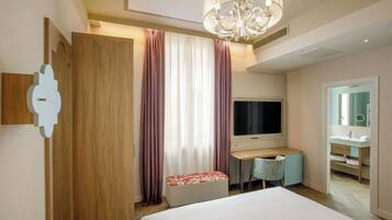 A hotel room with a bed, a desk, a TV, a chair, and a bathroom visible through an open door.