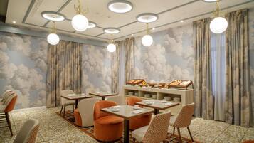 Un espace repas avec des tables rondes, des chaises et un buffet proposant divers plats.