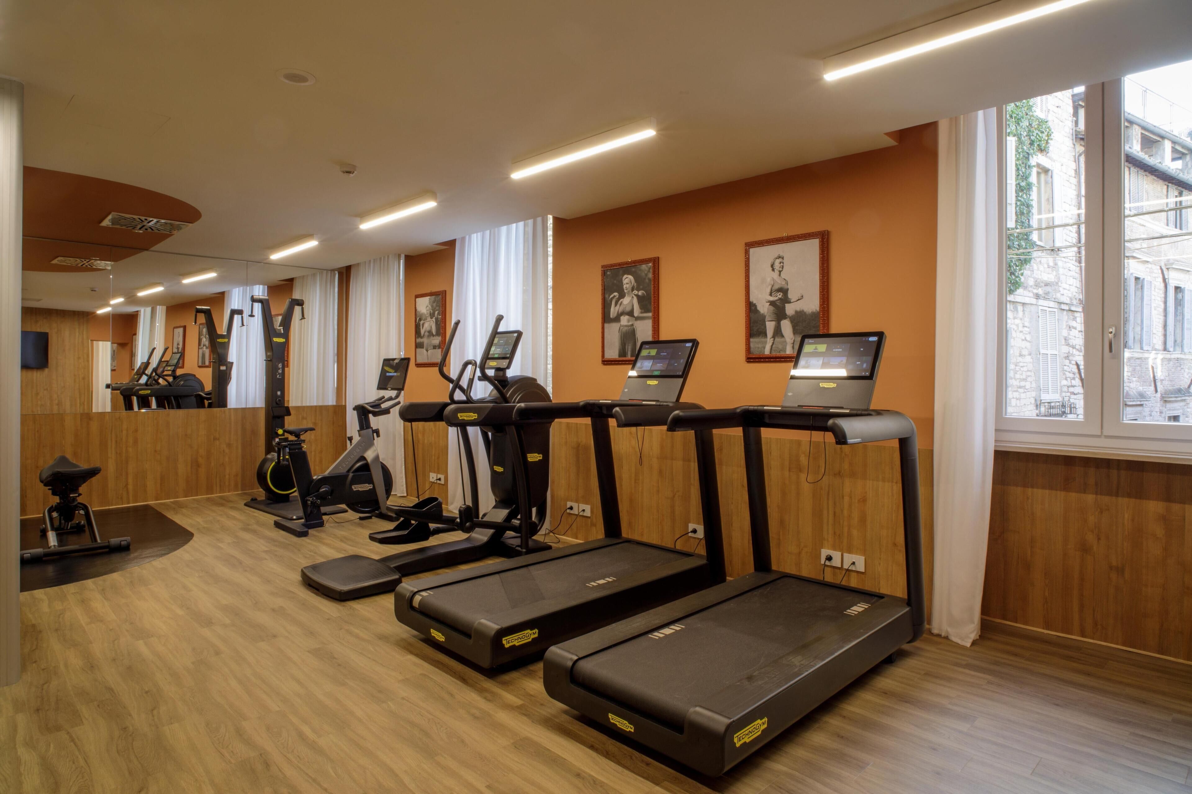 Un gimnasio con cintas de correr, bicicletas estáticas y máquinas elípticas.
