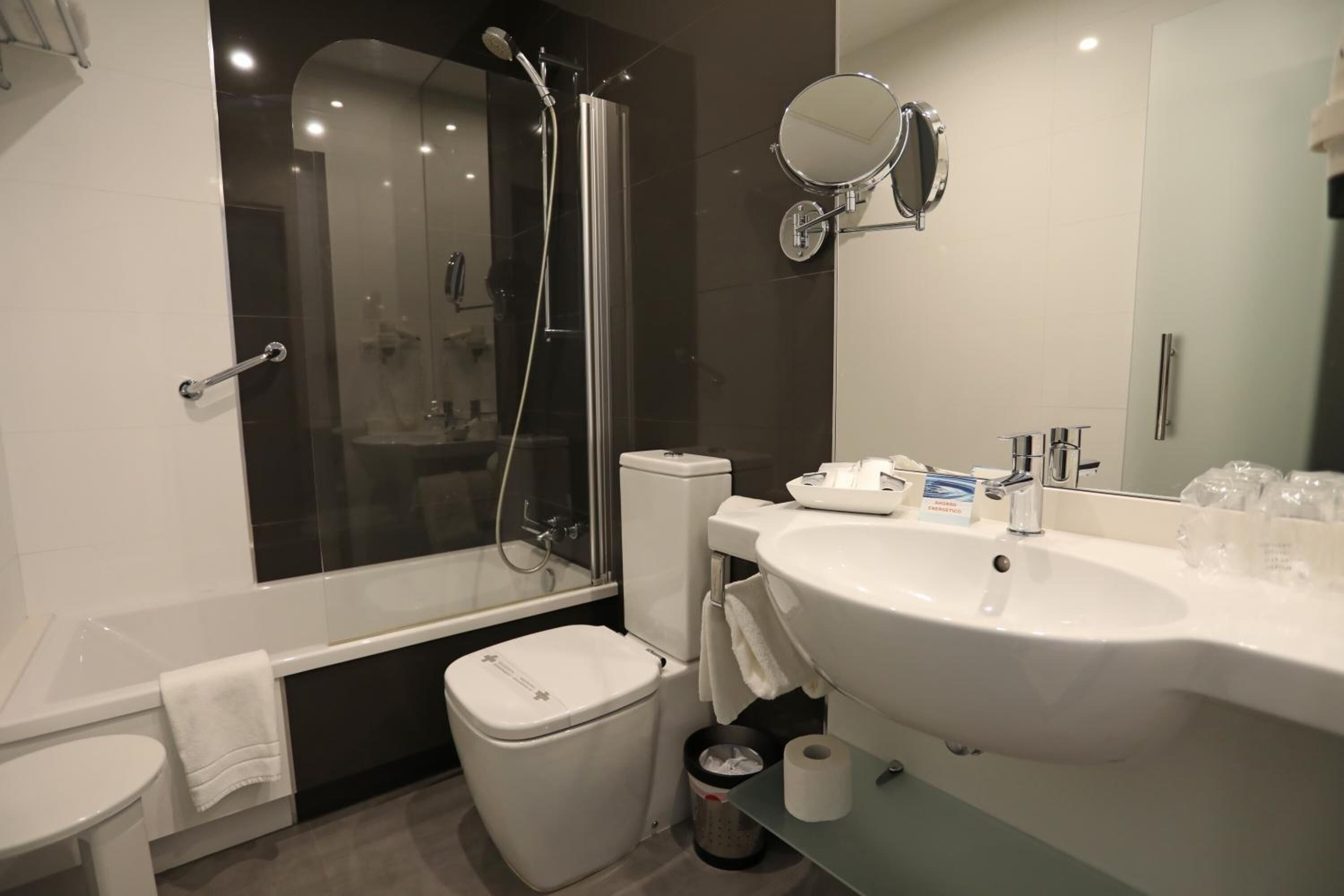 Ein modernes Badezimmer mit einer begehbaren Glasdusche, einem weißen Waschbecken und einer Toilette.