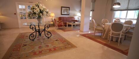 A hotel lobby with a round table, chairs, a sofa, and a chandelier.