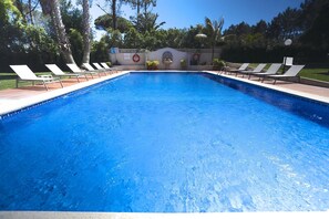 A swimming pool with white lounge chairs and a lifebuoy on the wall.