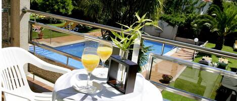 En balkon med et bord, to stole og et glas appelsinjuice.