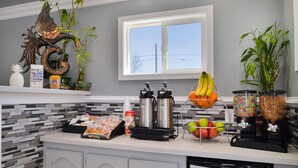 A kitchen with a coffee maker, blender, and fruit bowl.