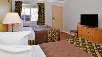 Una habitación de hotel con dos camas, televisión, escritorio y una silla.